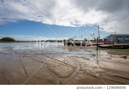 View of the quay showing mud at low tide on the River Deben in the historic town of Woodbridge in Suffolk, UK. View of the quay showing mud at low tide on the River Deben in the historic town of Woodbridge in Suffolk, UK. 129696690
