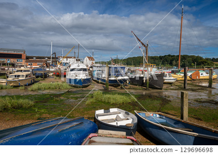 Small boats on a sunny day. View of the quay at low tide on the River Deben in the historic town of Woodbridge in Suffolk, UK. 129696698