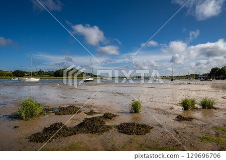 River Deben at low tide with small boats on a sunny day. View near the historic town of Woodbridge in Suffolk, UK. River Deben at low tide with small boats on a sunny day. View near the historic town of Woodbridge in Suffolk, UK. 129696706