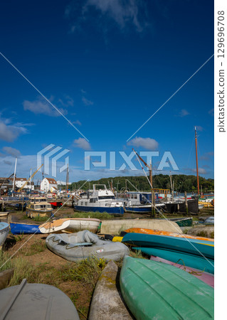 Colorful boats on a sunny day. View of the quay on the River Deben in the historic town of Woodbridge in Suffolk, UK. Colorful boats on a sunny day. View of the quay on the River Deben in the historic town of Woodbridge in Suffolk, UK. 129696708