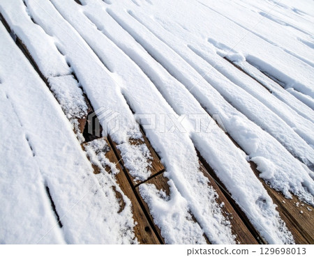 Snow Covered Wooden Deck Boards with Brown Wood Grain Detail in Winter 129698013