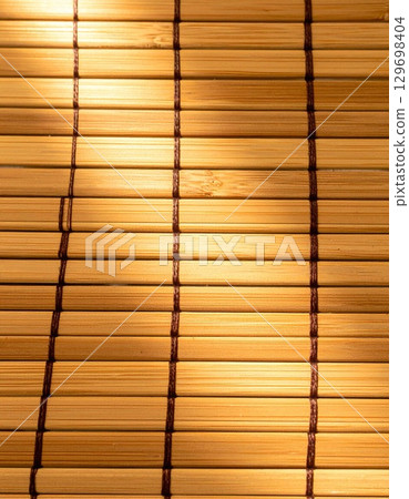 Closeup of Light Brown Bamboo Mat with Woven Pattern Texture Background with Natural Light 129698404