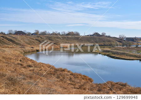 Serene riverbend in autumn landscape with clear blue sky and distant rural homes Serene riverbend in autumn landscape with clear blue sky and distant rural homes 129699948