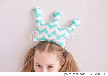 Young caucasian girl with chevron crown pillow on head playful pose 129700111