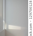 A minimalist landscape of light and shadows from a window reflected on a white wall 129700128