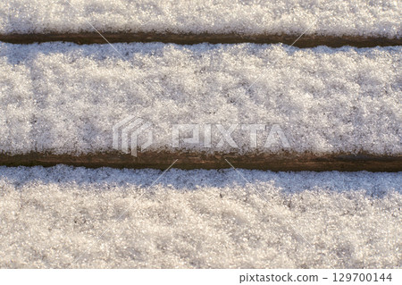 Close-up of snow-covered wooden steps in winter outdoor scene 129700144