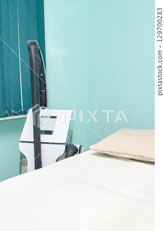 Empty modern clinic room with white bed and advanced medical equipment in clean Empty modern clinic room with white bed and advanced medical equipment in clean 129700283
