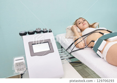 Young caucasian female undergoing non-invasive body contouring treatment Young caucasian female undergoing non-invasive body contouring treatment 129700293