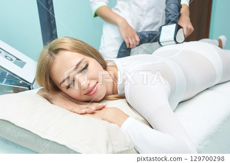 Caucasian female receiving body contouring treatment with relaxed expression 129700298