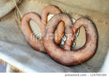 Two fresh cinnamon sugar pretzels on a burlap cloth, ready to be served 129700380