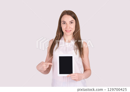 Caucasian adult female holding tablet displaying pointing gesture in minimalist Caucasian adult female holding tablet displaying pointing gesture in minimalist 129700425