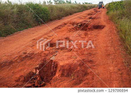 Red dust and mud road in poor condition with large holes and bumps formed after rain. Routes to Andringitra national park are extremely bad during wet season in region near Sendrisoa, Madagascar Red dust and mud road in poor condition with large holes and bumps formed after rain. Routes to Andringitra national park are extremely bad during wet season in region near Sendrisoa, Madagascar 129700894