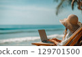 Woman working on laptop by the ocean, enjoying remote work and seaside freedom 129701500