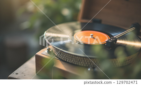 Nostalgic vinyl experience: Turntable playing retro record amidst blurred green foliage in a soft light 129702471