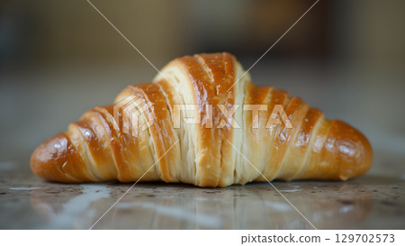 Delicious buttery croissant on a table ready for breakfast, it's looking flaky, fresh and baked to perfection 129702573