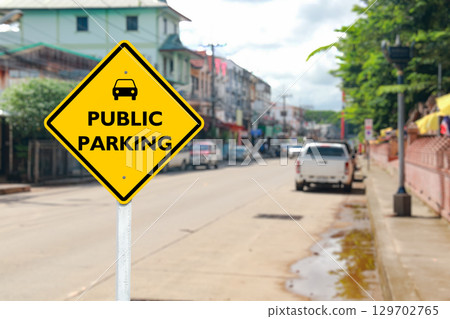 Yellow Public Parking Sign on Blurred Community Road Yellow Public Parking Sign on Blurred Community Road 129702765