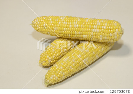 Three raw cobs of sweet corn against background. Tasty sweet corn on cobs Three raw cobs of sweet corn against background. Tasty sweet corn on cobs 129703078