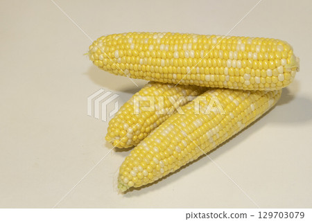 Three raw cobs of sweet corn against background. Tasty sweet corn on cobs Three raw cobs of sweet corn against background. Tasty sweet corn on cobs 129703079