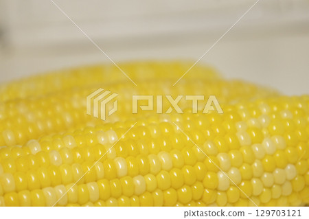 Close cooked cob of sweet corn against background. Tasty sweet corn on cob. Close cooked cob of sweet corn against background. Tasty sweet corn on cob. 129703121