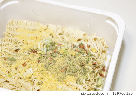 Raw instant noodles with spices on white plastic box. 129703156