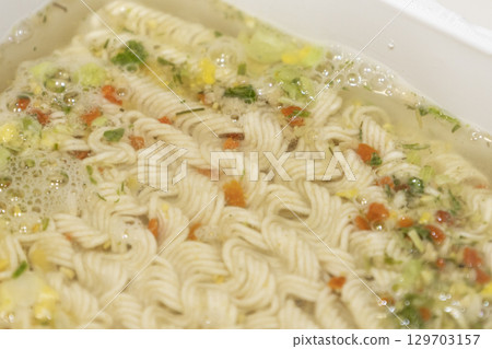 Instant noodles with spices and water on white plastic box. Instant noodles with spices and water on white plastic box. 129703157