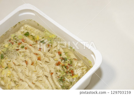 Instant noodles with spices and water on white plastic box. Instant noodles with spices and water on white plastic box. 129703159