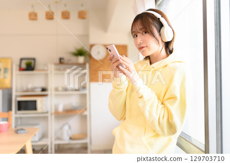 一位身穿黃色連帽衫的女士正在欣賞音樂 129703710