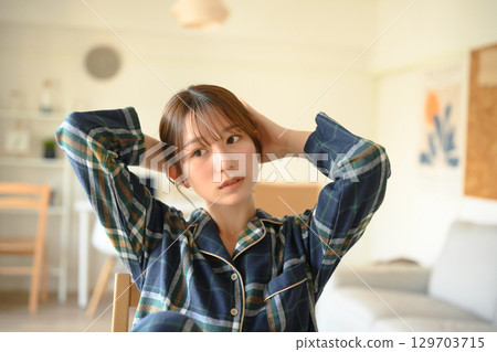 A woman in pajamas fixing her hair A woman in pajamas fixing her hair 129703715