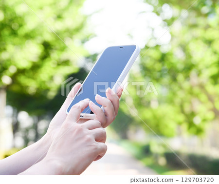 A woman operating a smartphone outdoors 129703720