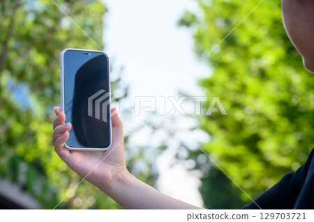 A woman operating a smartphone outdoors 129703721