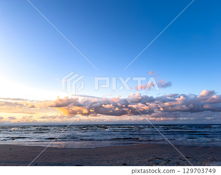 Beautiful sunset over calm ocean waves with colorful clouds in the evening sky 129703749
