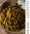 Unique culinary delicacy featuring fried insects in a glass jar at a local market 129703753