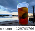 Refreshing beverage by the water at sunset, showcasing vibrant colors and evening tranquility 129703766