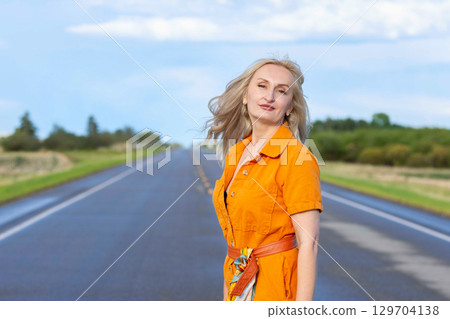 Blonde free woman is on the empty rural road in summer. Blonde free woman is on the empty rural road in summer. 129704138