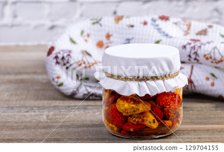 Cherry dried tomatoes in a jar with herbs and oil. Cherry dried tomatoes in a jar with herbs and oil. 129704155