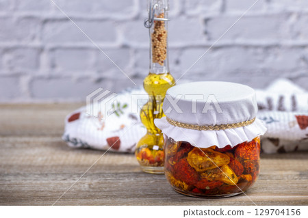 Cherry dried tomatoes in a jar with herbs and oil. Cherry dried tomatoes in a jar with herbs and oil. 129704156