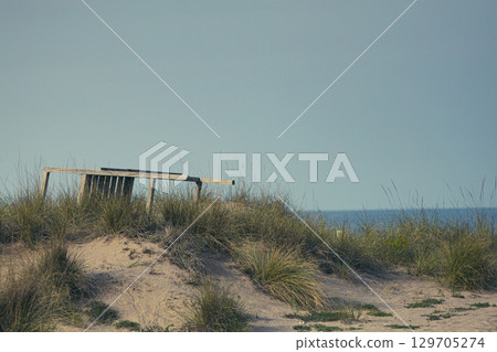 Single old folding chair in sand 129705274