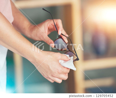 Hands, spectacles and cleaning for sight, vision or eyewear hygiene to see clearly with sanitizing wipe. Hand of person wiping pair of transparent glasses with cloth for hygienic eye care or eyesight 129705452