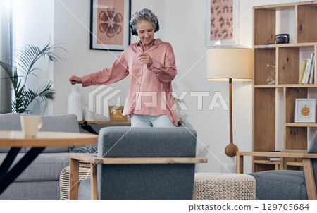 Mature, music and woman with headphones for dance, freedom and streaming audio in the lounge. Fun, enjoyment and dancing elderly person with a podcast, radio or listening to a sound for happiness 129705684