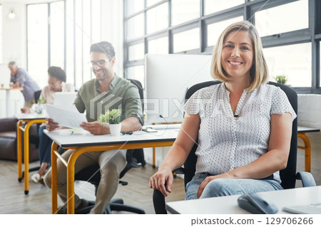 Business woman, smile and sitting at the desk happy for career, vision or ambition at office. Portrait of young female designer smiling in happiness for job, profession or occupation at the workplace 129706266