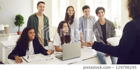 High school students at the lesson in classroom with laptop listening a teacher during a lesson. High school students at the lesson in classroom with laptop listening a teacher during a lesson. 129706295