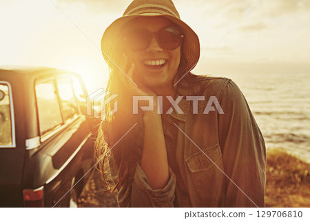Portrait, sunset and road trip with a black woman outdoor enjoying travel as a tourist by the sea or ocean in nature. Beach, car and summer with a female tourist taking a scenic drive on the coast 129706810