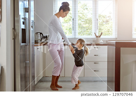 Kitchen dancing, mother and daughter in the morning at home with happiness dancing together. Mom, girl and parent care holding hands with a young kid in a house happy about family with a smile 129707046