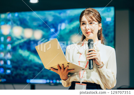 Businesswoman speaking into a microphone in the office 129707351