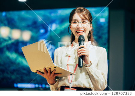 Businesswoman speaking into a microphone in the office 129707353