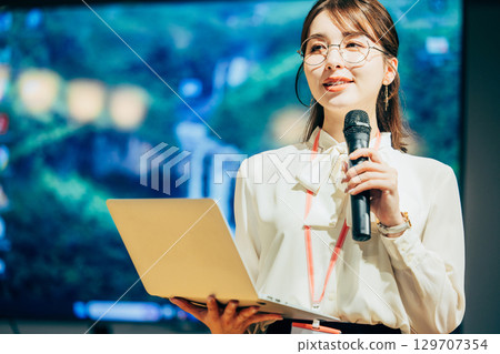 Businesswoman speaking into a microphone in the office 129707354