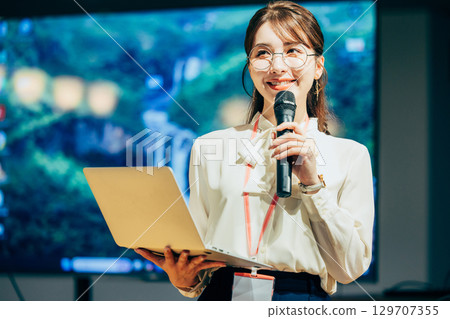 Businesswoman speaking into a microphone in the office 129707355