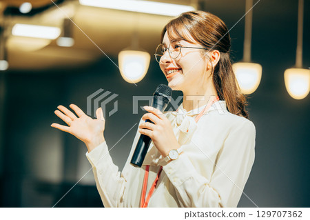 Businesswoman speaking into a microphone in the office 129707362