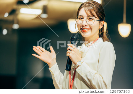 Businesswoman speaking into a microphone in the office 129707363