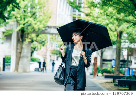 拿著遮陽傘的年輕女商人 129707369